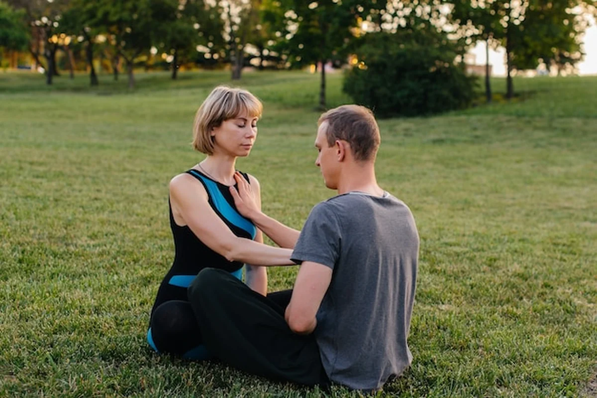Grupa osób wykonuje jogę w parku podczas zachodu słońca