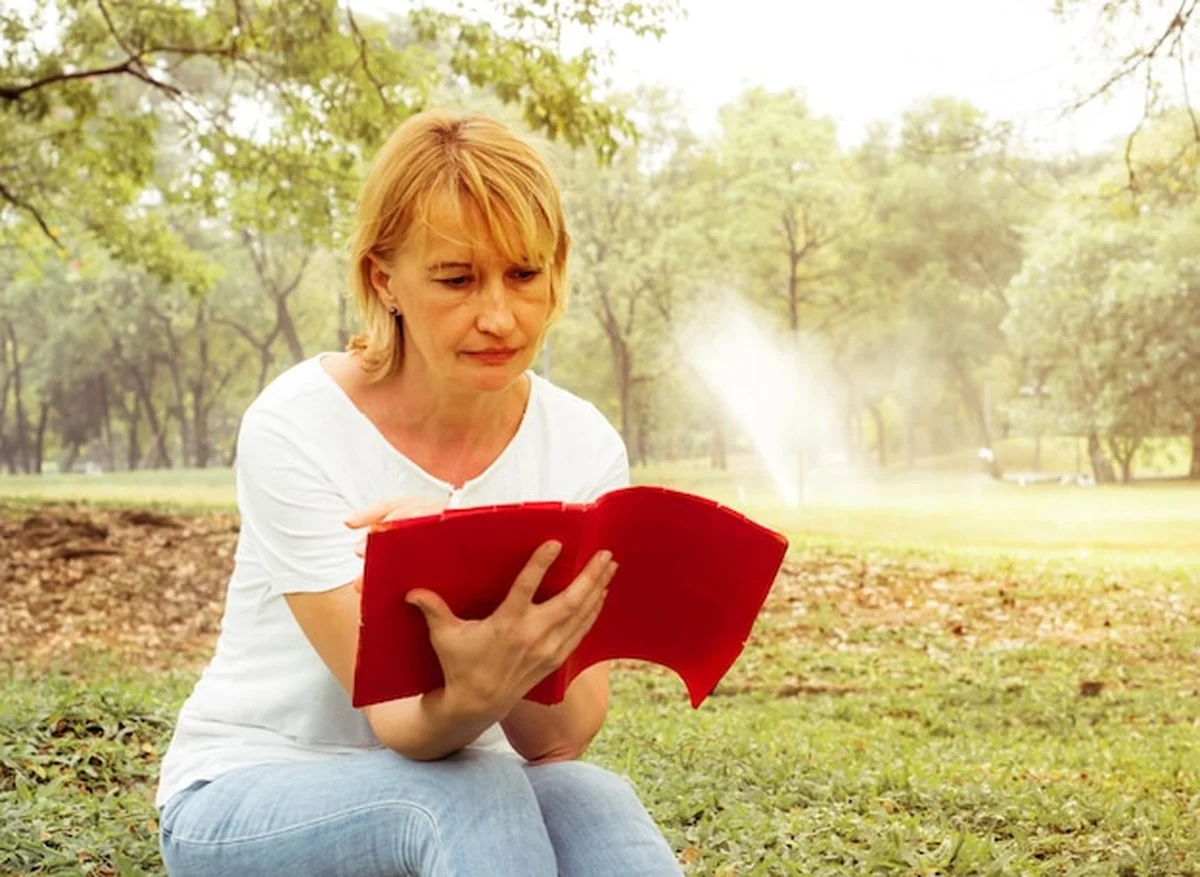 Kobieta czyta książkę w parku